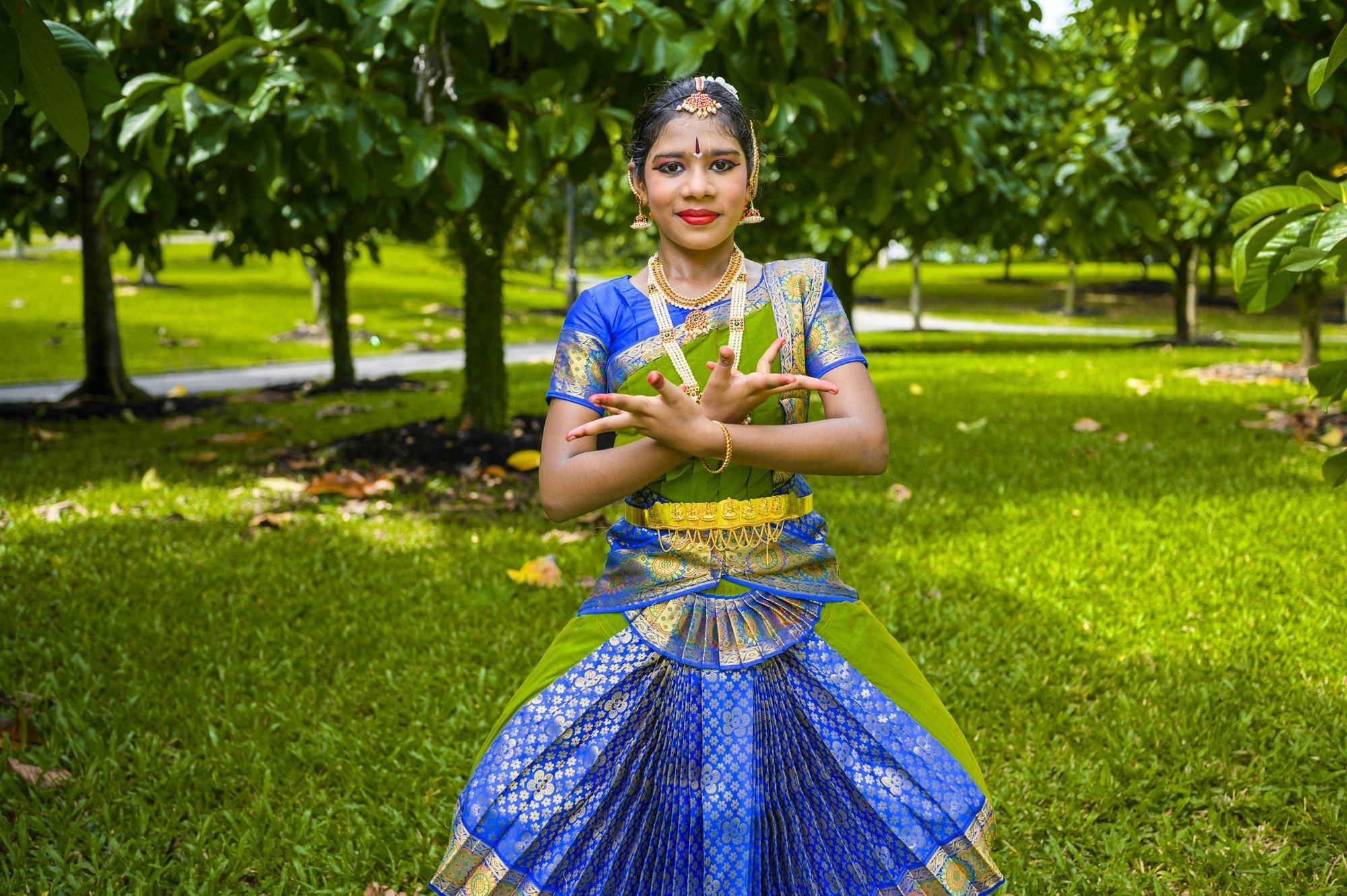 A student in a blue costume dancing in a wide stance