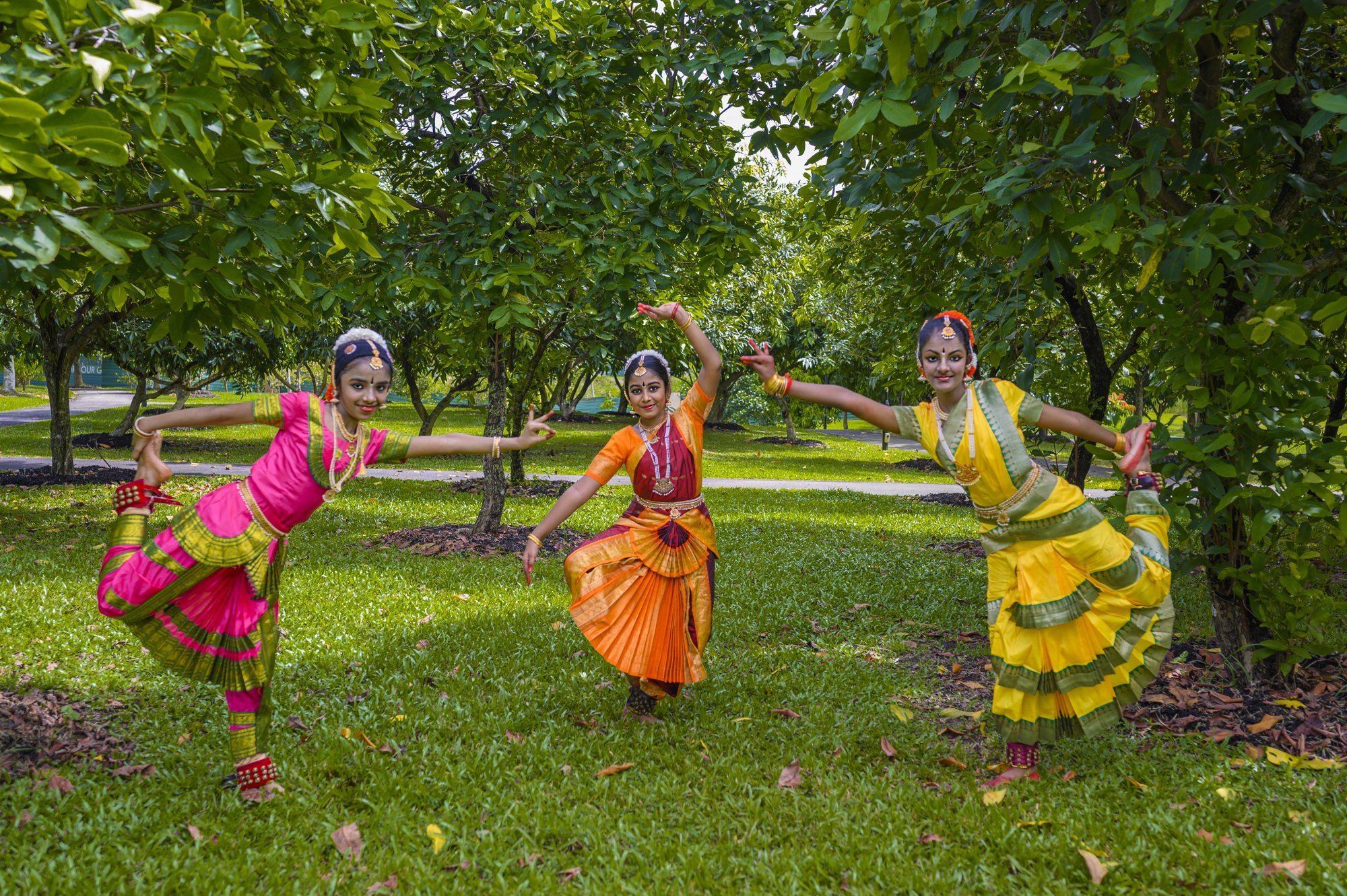 Three students dancing a group item among the trees
