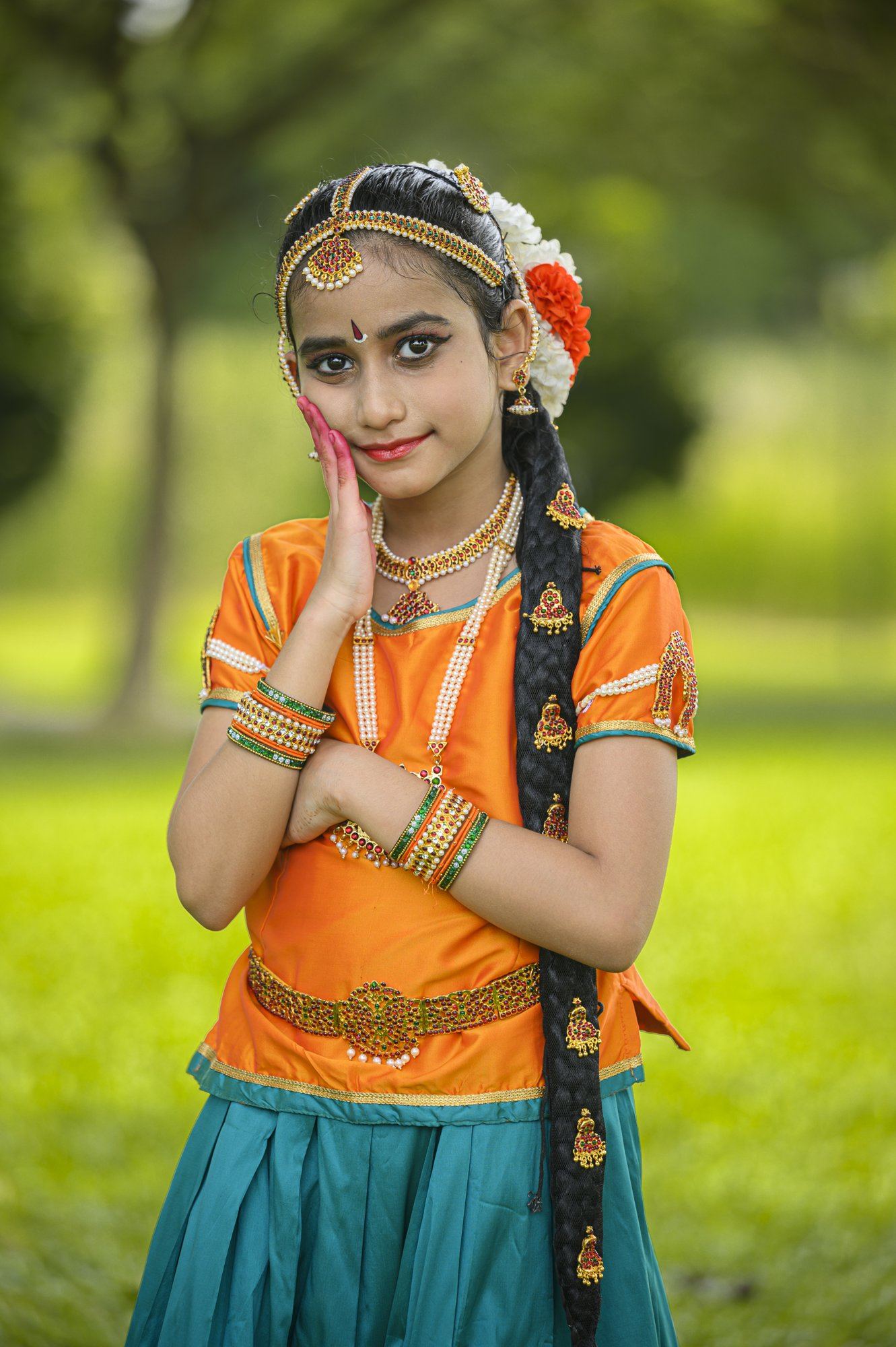A smiling young dancer in an orange and teal costume