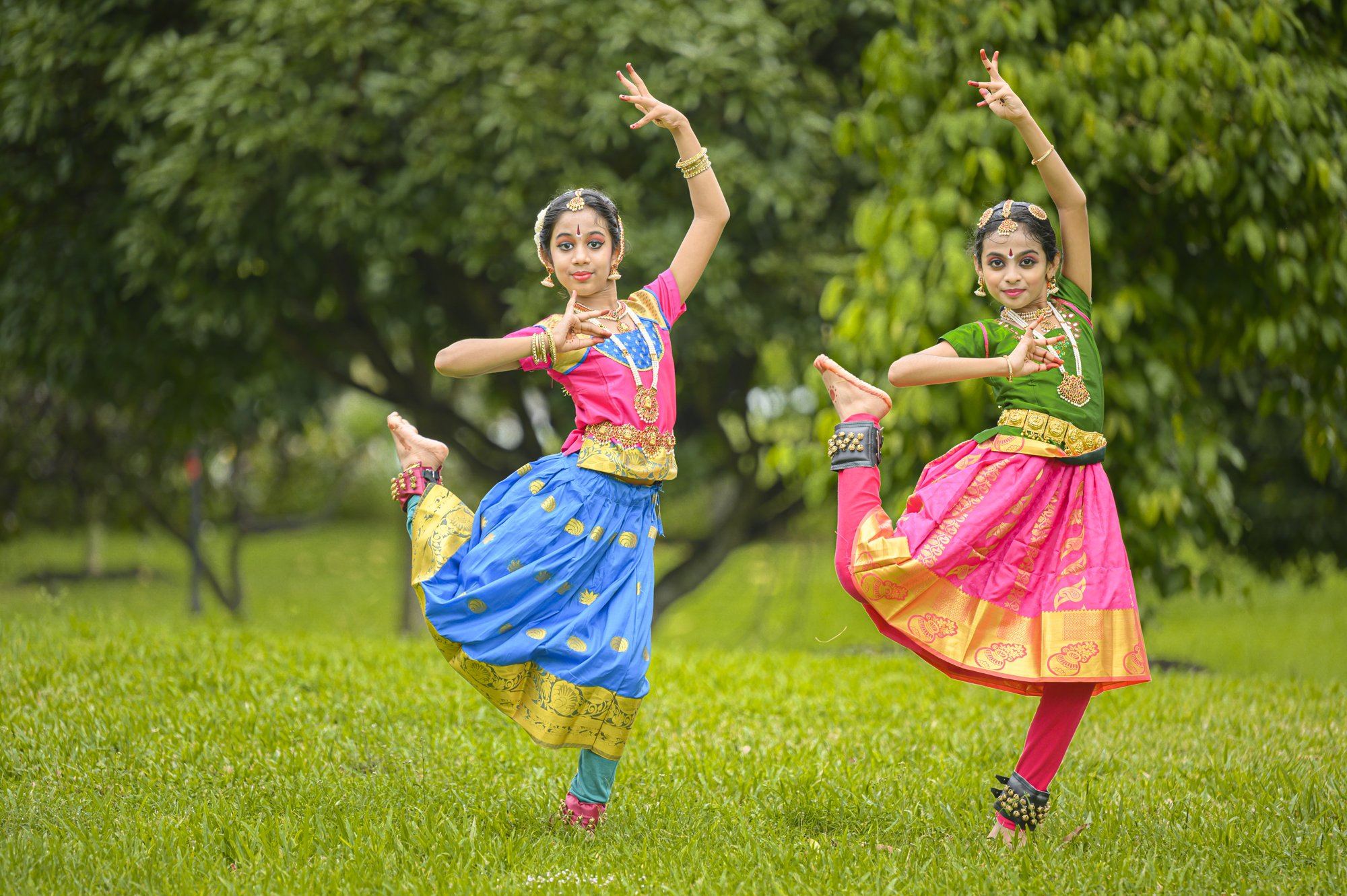 Two students dancing a Bharatanatyam duet in mirrored poses