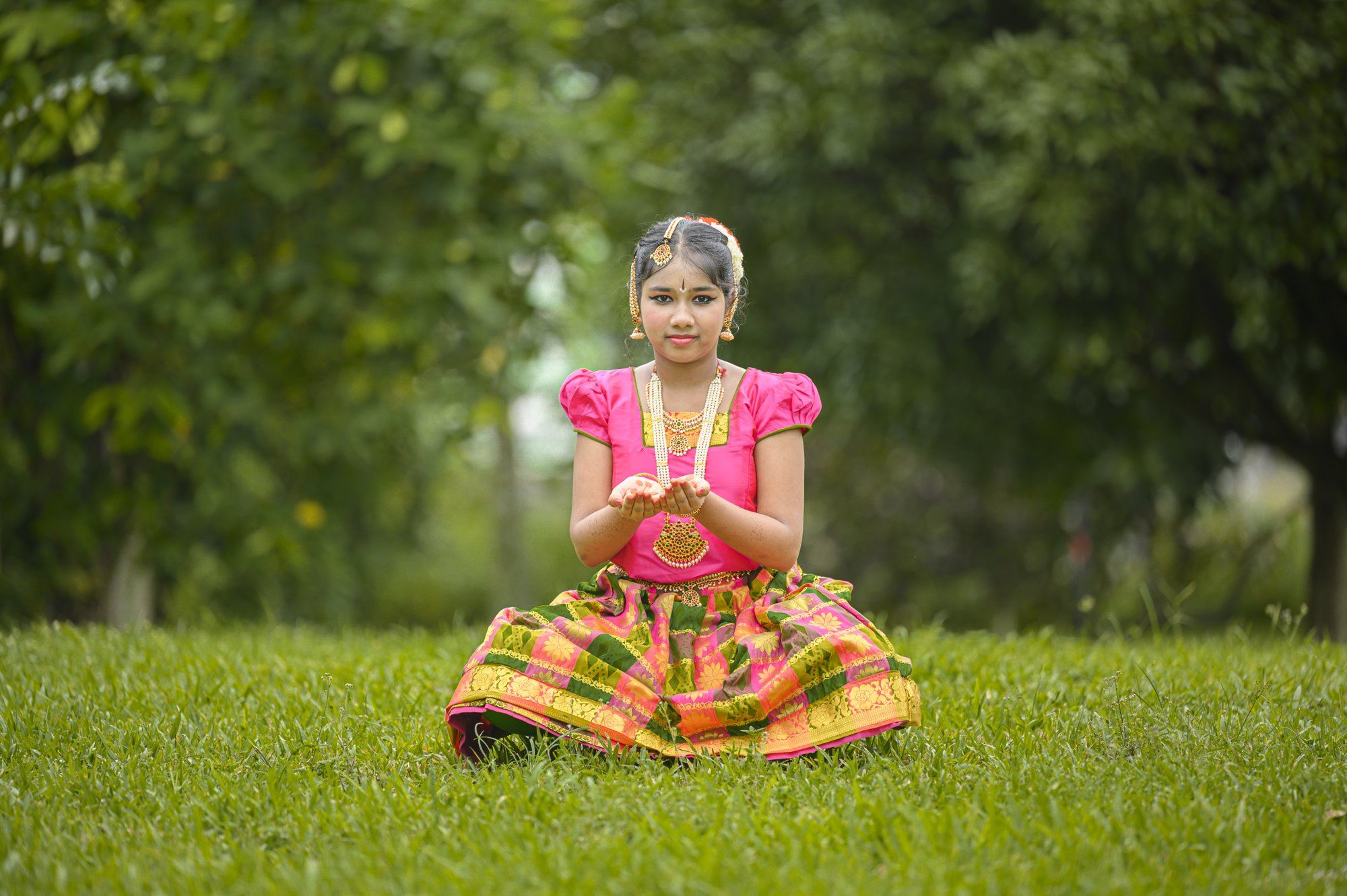 A young student seated in a Bharatanatyam pose
