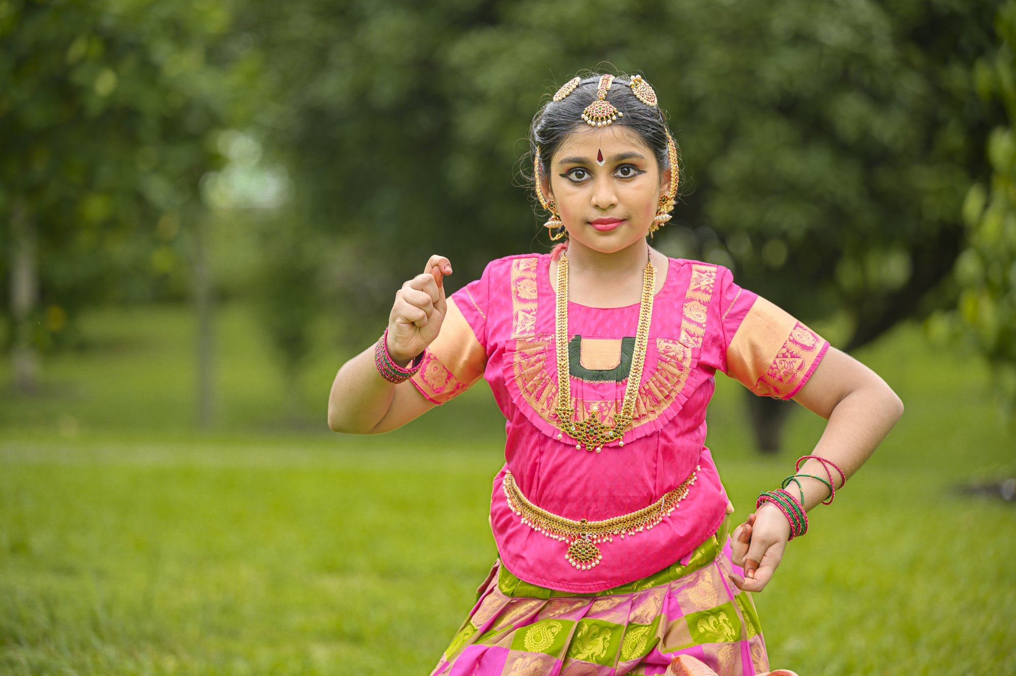 A smiling student in a pink costume with hands on hips