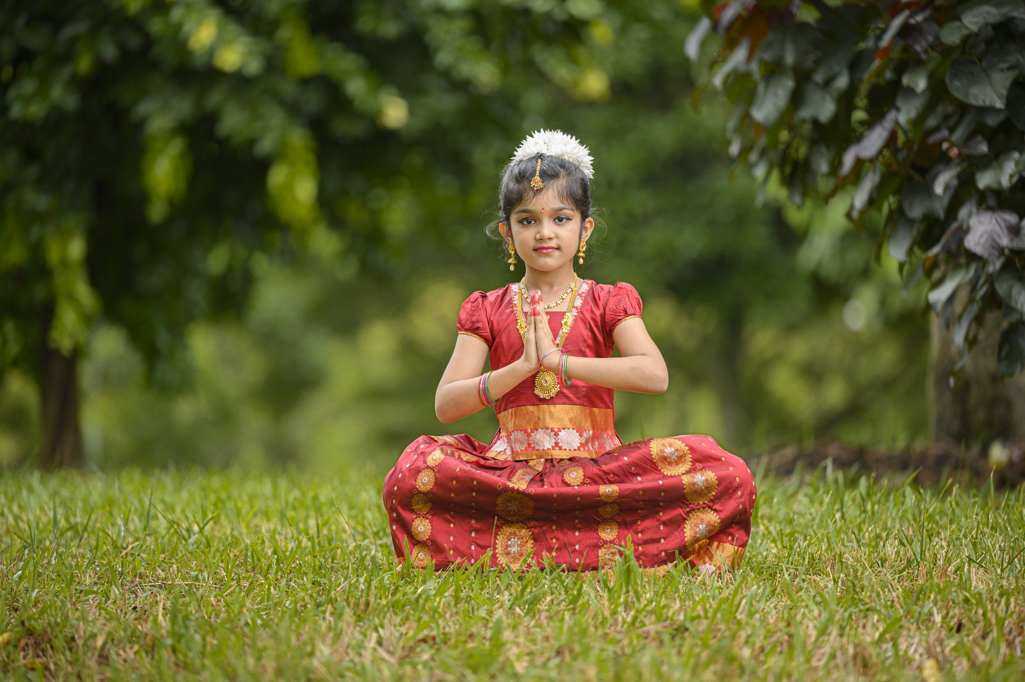 A young student seated in a Bharatanatyam pose with hands in prayer