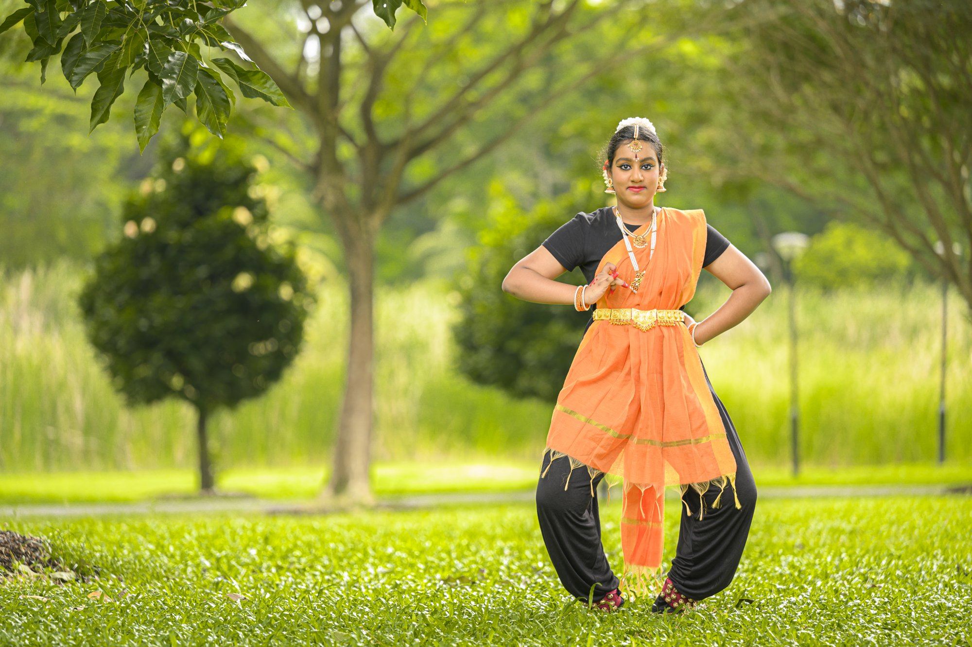 A senior student in an orange costume in a wide stance